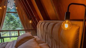 A cozy bedroom with a bed, a hanging light fixture, and a window with curtains.