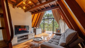 Moderni olohuone, jossa on televisio, jossa näkyy teksti »NETFLIX», sohva, sohvapöytä ja takka.