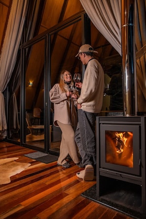 A cozy room with a large glass door, a fireplace, and a wooden floor. - Pousada Refúgio da Boa Vista (Urubici)