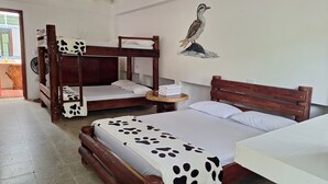 Quarto com duas beliches, uma mesa de madeira com toalhas e uma obra de arte na parede.