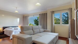 A modern bedroom with a sofa bed, a separate bed, a nightstand, and a window with curtains. - Holiday Home 'Refugio Dourado' with Sea View, Shared Garden and Wi-Fi Access (Água de Pena)