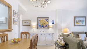 A dining area with a wooden table, chairs, a white cabinet, and a painting on the wall.