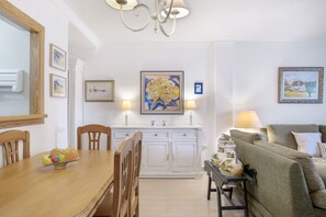 Un coin repas avec une table en bois, des chaises, un buffet blanc et un tableau accroché au mur.