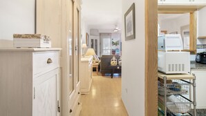 A hallway with a white cabinet, a lamp, a chair, and a microwave.