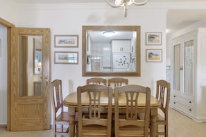 A dining area with a wooden table and chairs, a mirror on the wall, and framed pictures.