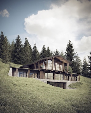 Una casa moderna con fondamenta in pietra, ampie finestre e struttura in legno, situata su una collina erbosa.