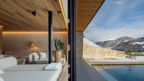 Ein moderner Wellnessraum mit Steinwand, Pool und Bergblick.