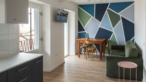 A modern kitchen with a dining area, featuring a geometric wall design and a view of a balcony.