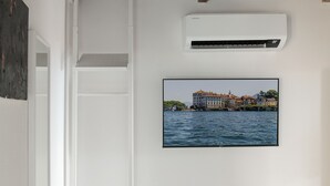 A wall-mounted air conditioner and a framed picture of a waterfront building.