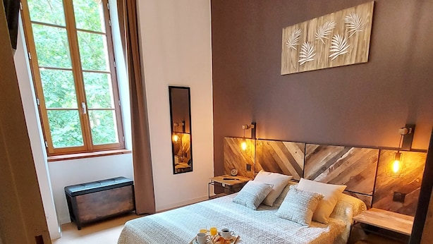 A neatly made bed with a tray of breakfast items, a bedside table with a lamp, and a large window with curtains. - Magnificent 3 stars flat (Aulus-les-Bains)