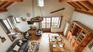 A spacious living area with a dining table, sofas, and a kitchen with wooden cabinets. - Chalet "Eterlou" with Mountain View, Balcony and Wi-Fi (Lanslebourg Mont-Cenis)