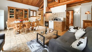 A spacious living area with a dining table, sofa, and kitchen in a rustic wooden cabin. - Chalet "Eterlou" with Mountain View, Balcony and Wi-Fi (Lanslebourg Mont-Cenis)