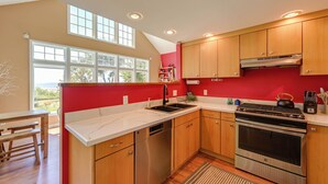 A kitchen with wooden cabinets, a stainless steel dishwasher, and an oven. - Waterfront Bellingham Bliss: Steps to Beach! (Bellingham)