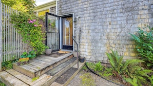 A wooden exterior with a door, steps, and a small garden area with plants and a fence. - Waterfront Bellingham Bliss: Steps to Beach! (Bellingham)