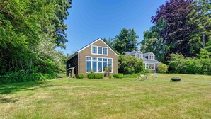 A house with a large lawn, a patio with chairs, and a small garden. - Waterfront Bellingham Bliss: Steps to Beach! (Bellingham)