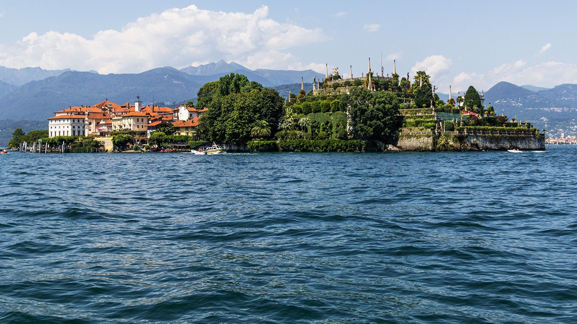 A waterfront property with buildings, a garden, and a view of mountains.