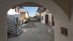Un pati amb sòl de pedra, una escala i vista als edificis circumdants.