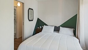 A bedroom with a bed, a nightstand, and a mirror.