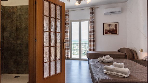 Una habitación de hotel con ducha, cama y toallas, un balcón y una lámpara en el techo.