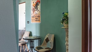 Una habitación pequeña con un cartel en la pared, una silla, una mesa y una planta.