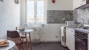 Una cocina con una mesa de comedor, sillas, un microondas y una estufa.