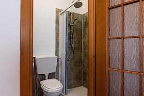A bathroom with a shower, toilet, and a wooden door. - Room 'Stanza Frutta' with Wi-Fi and Air Conditioning (Agrigento)