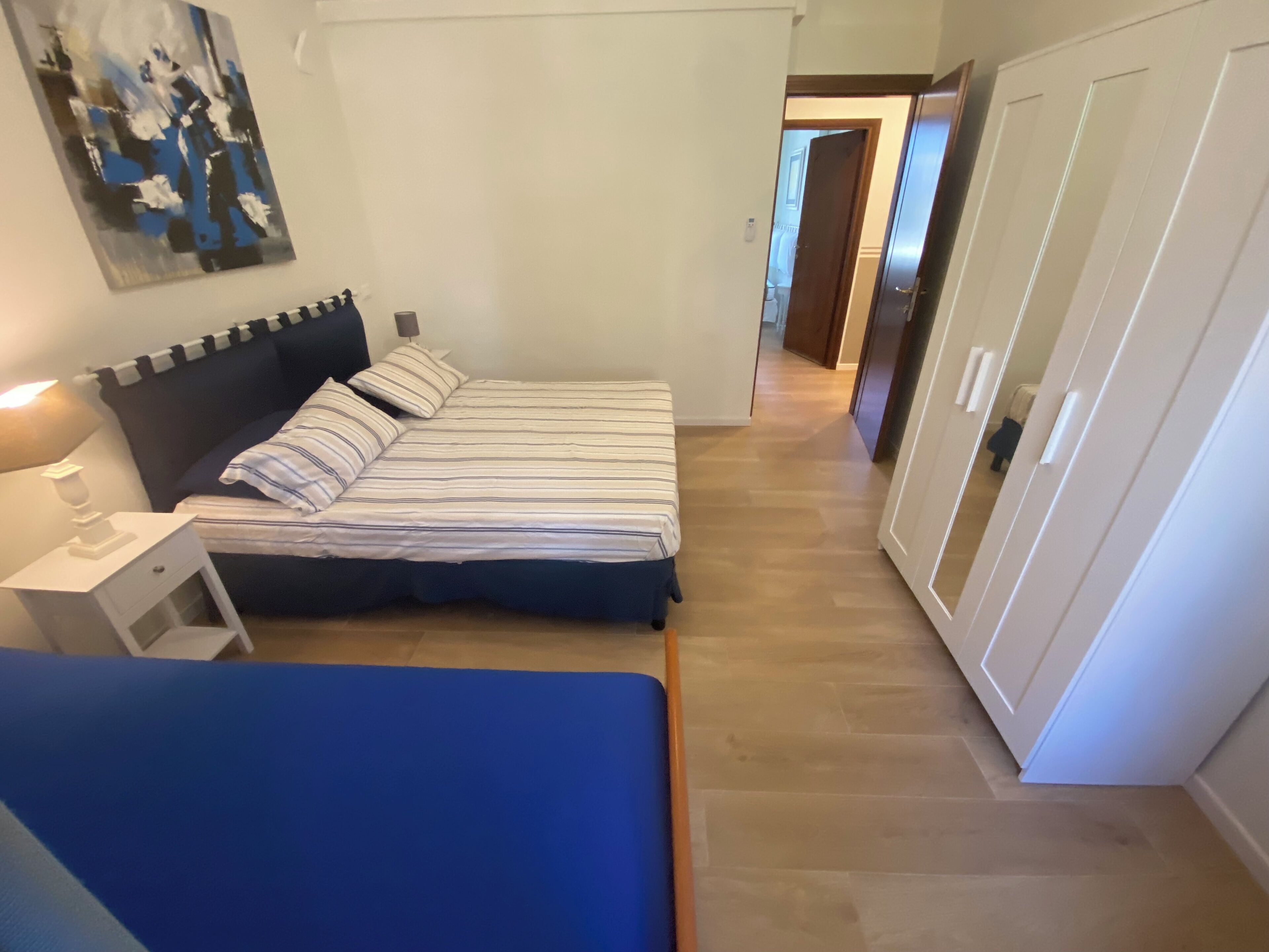 Un dormitorio con cama, mesita de noche y un cuadro en la pared.