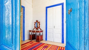 Une pièce avec une porte blanche, une porte bleue, un miroir et un tapis à motifs.