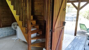 A wooden staircase with a fan and a chair outside.