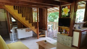 A wooden interior with a staircase, white furniture, a TV, and a kitchen area.