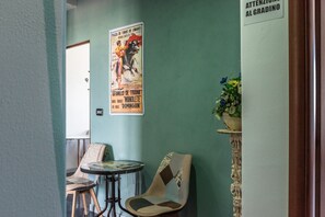 Une petite pièce avec une affiche accrochée au mur, une chaise, une table et une plante.