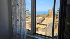 A room with a view of buildings and the sea through a window. - Room 'Stanza Fiore' with Wi-Fi and Air Conditioning (Agrigento)