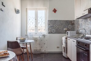 Una cocina con una mesa de comedor, sillas, un microondas y una estufa.