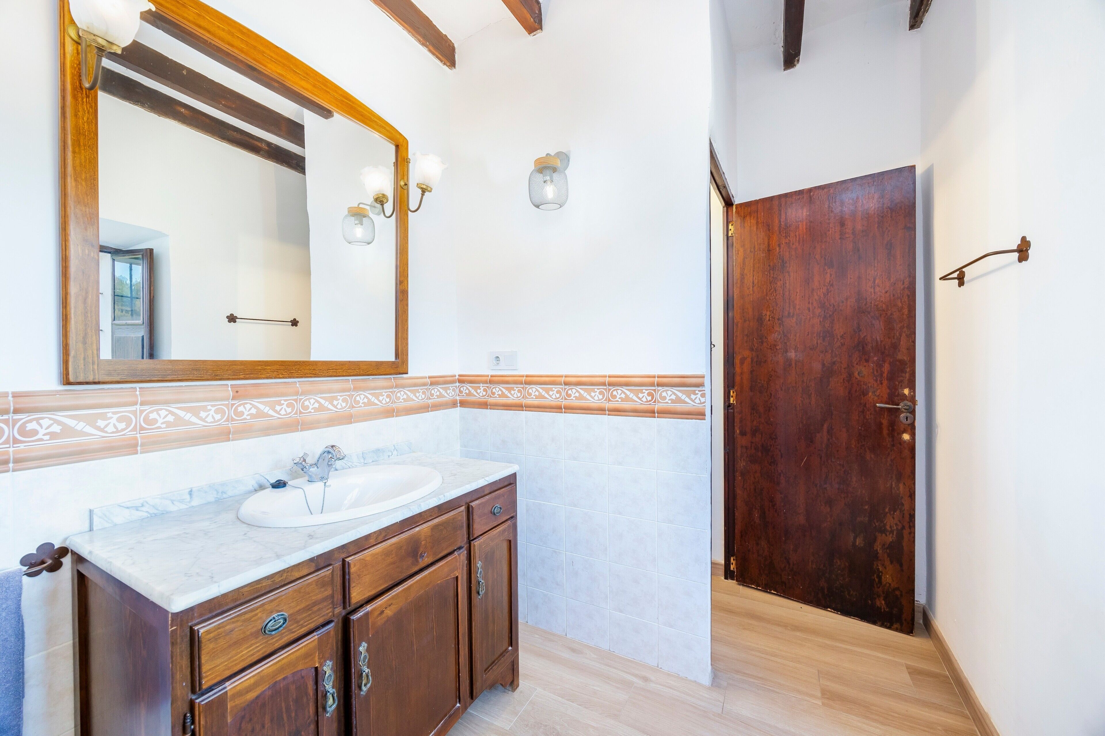 A bathroom with a wooden vanity, a large mirror, and a tiled backsplash.