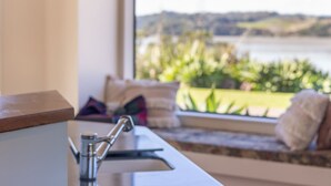 Una cocina moderna con un lavamanos de acero inoxidable y vistas a un lago a través de un amplio ventanal.