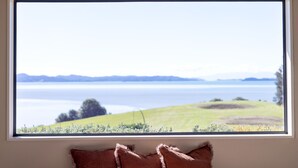Una ventana con vista a un lago y montañas a lo lejos.