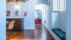 A narrow hallway with wooden flooring, a brown leather chair, a red cabinet, and a bench with cushions. - Libeccio Urban Suite by Pleiades Home (Livorno)