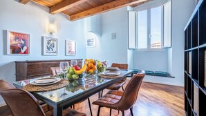 A dining area with a wooden ceiling, a glass table set for six, and a view of the city through a window. - Libeccio Urban Suite by Pleiades Home (Livorno)