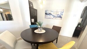 En matplats med ett runt bord, fyra stolar och en vas med blommor.