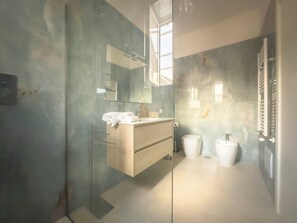 Un bagno moderno con cabina doccia in vetro, un mobile bagno in legno e uno specchio grande.