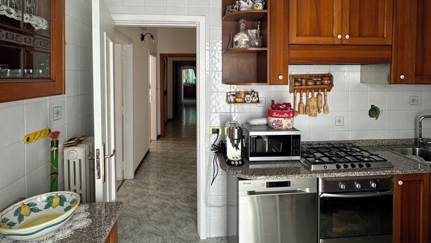 A modern kitchen with granite countertops, stainless steel appliances, wooden cabinets, and a visible doorway leading to another room. - Sorrento Coast - Casa Raffaella : spacious panoramic penthouse (Meta)
