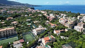 A coastal town with a mix of residential buildings, a sports field, and a view of the sea. - Sorrento Coast - Casa Raffaella : spacious panoramic penthouse (Meta)