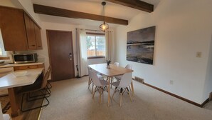 Eine moderne Küche mit Holzschränken, einer Mikrowelle und einem Essbereich mit Tisch und Stühlen.