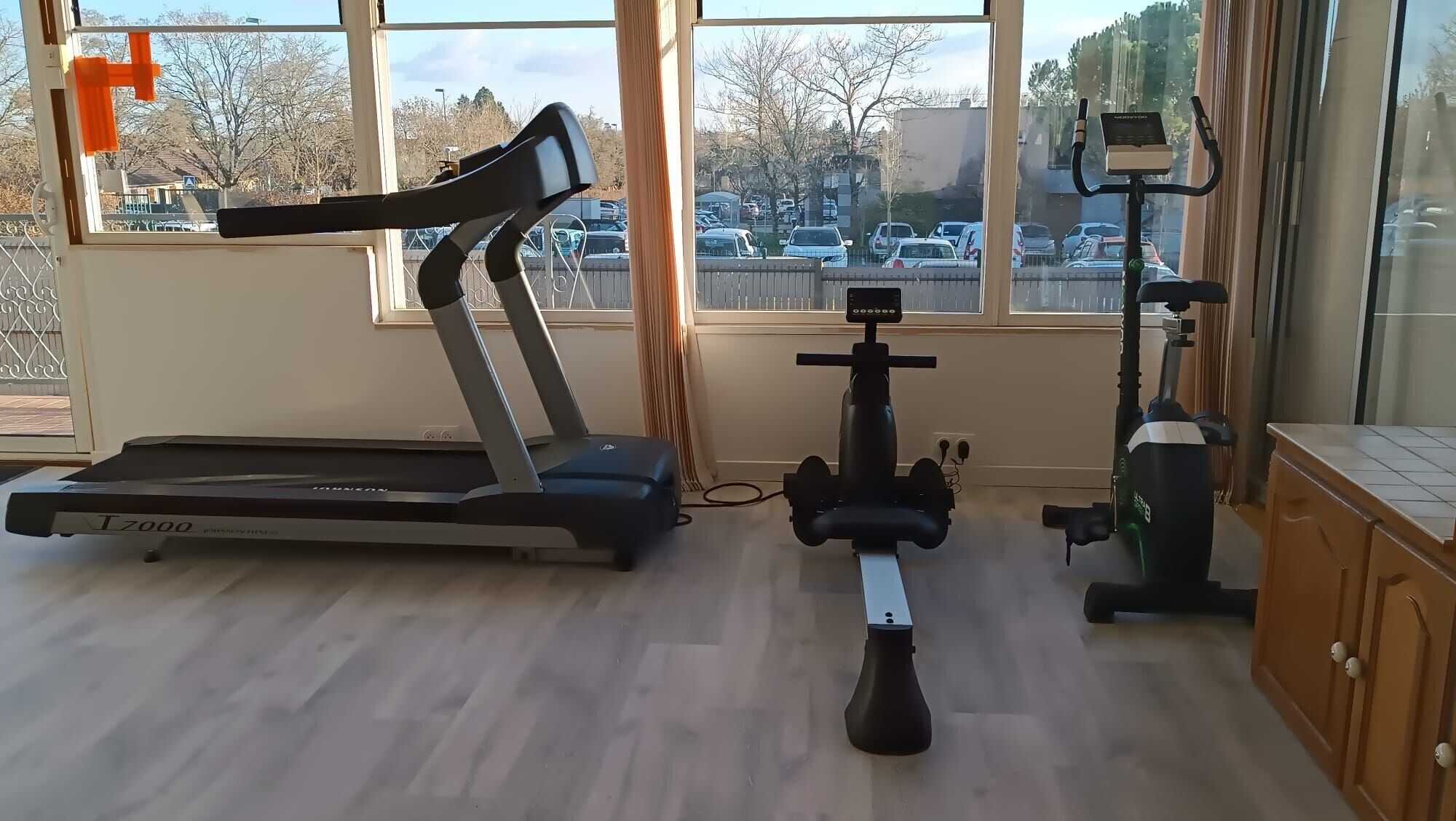 Une salle de sport à domicile équipée d’un tapis de course, d’un vélo d’appartement et d’un rameur.