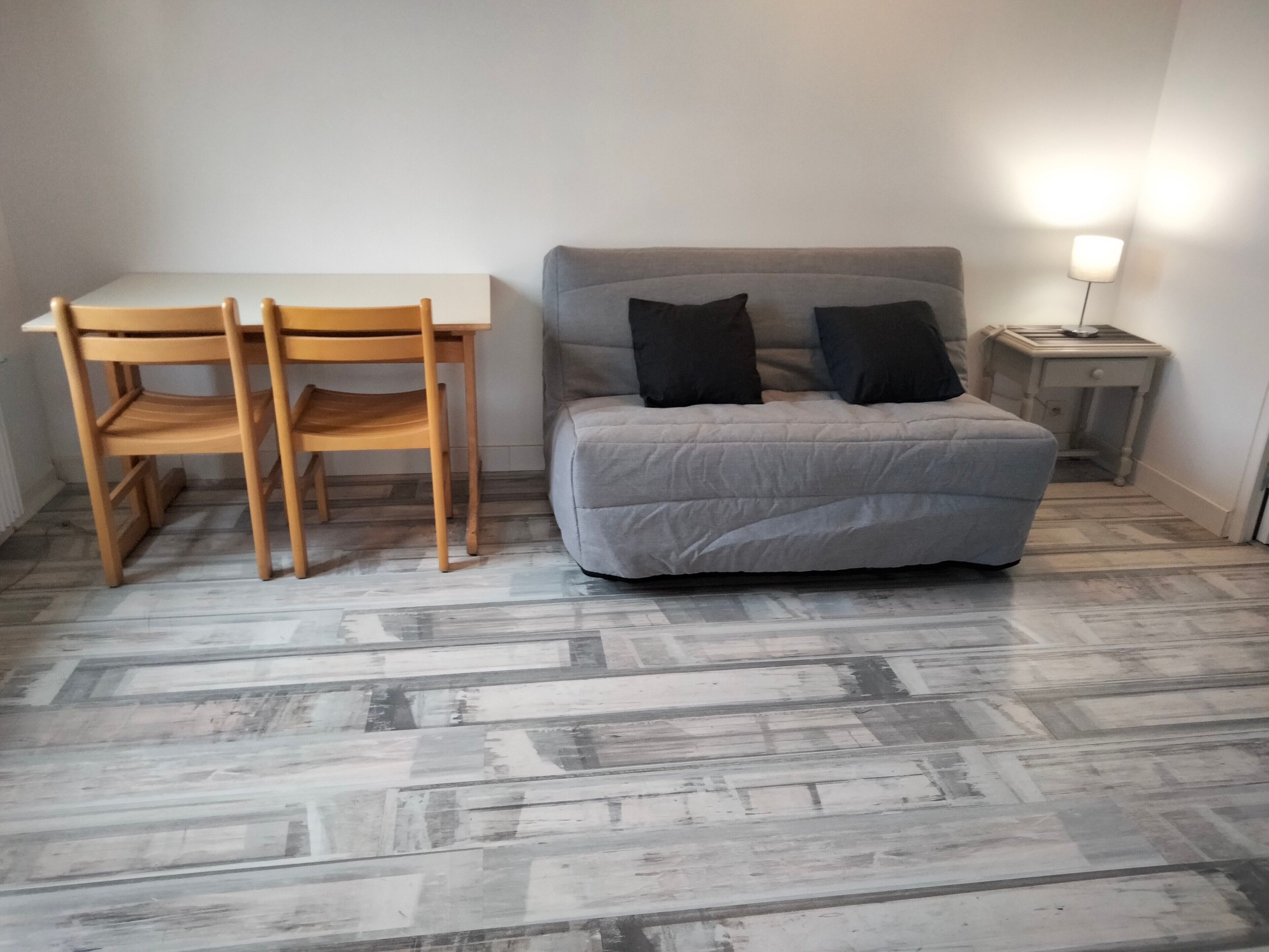 Ein Schlafzimmer mit einem Bett, zwei Stühlen, einem Nachttisch und einer Lampe.