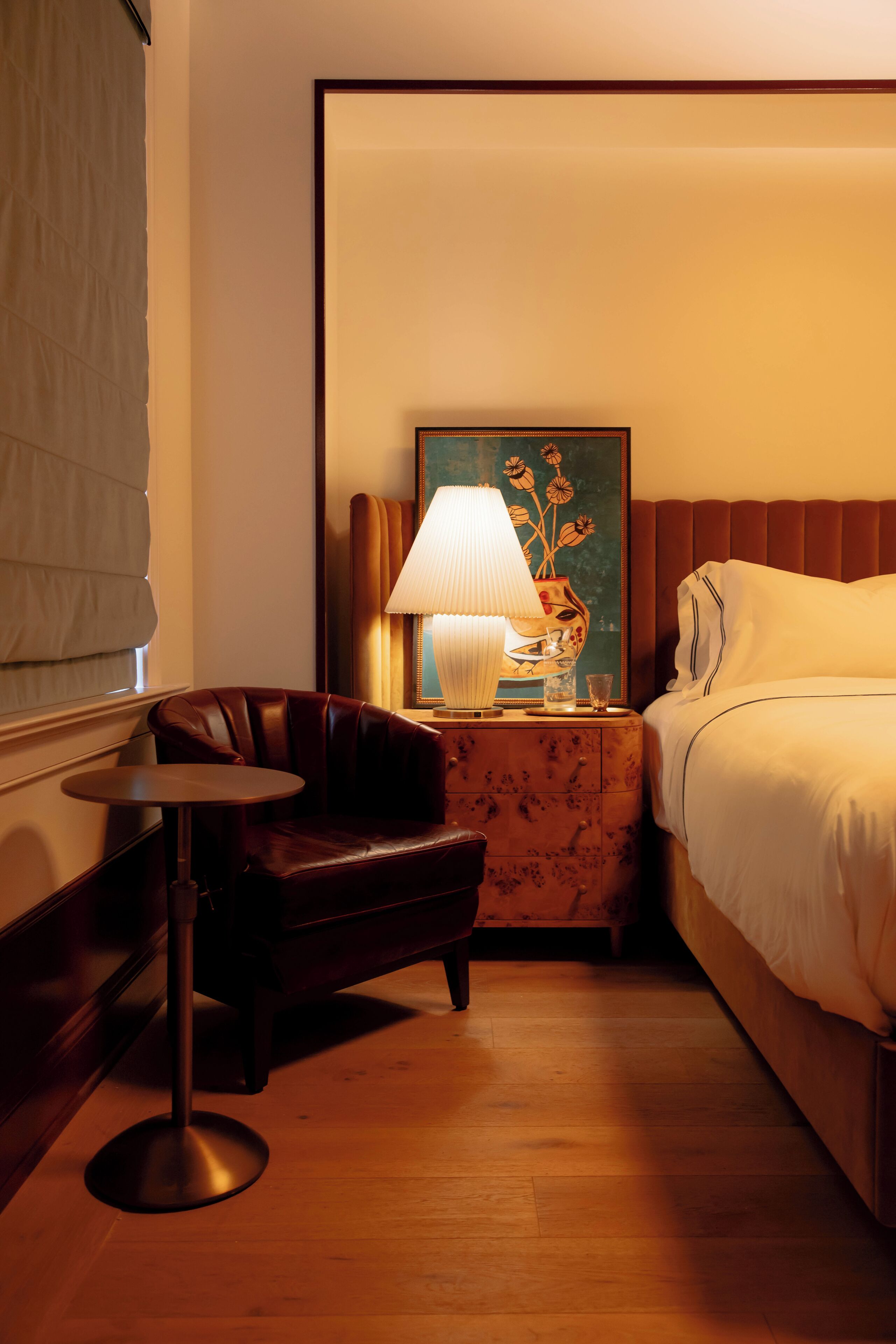 Ein Hotelzimmer mit Bett, einem kleinen Tisch, einem Stuhl, einer Lampe und einem Bild an der Wand.