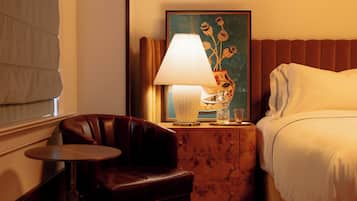 Ein Hotelzimmer mit Bett, einem kleinen Tisch, einem Stuhl, einer Lampe und einem Bild an der Wand.