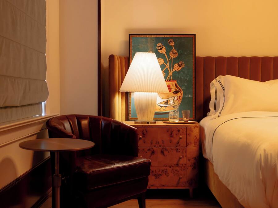 Ein Hotelzimmer mit Bett, einem kleinen Tisch, einem Stuhl, einer Lampe und einem Bild an der Wand.
