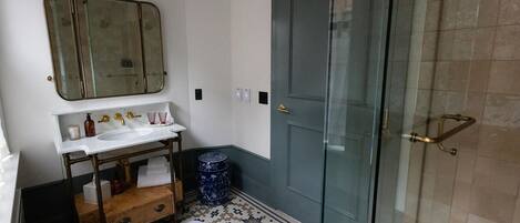 A bathroom with a white sink, mirror, and a glass shower door.