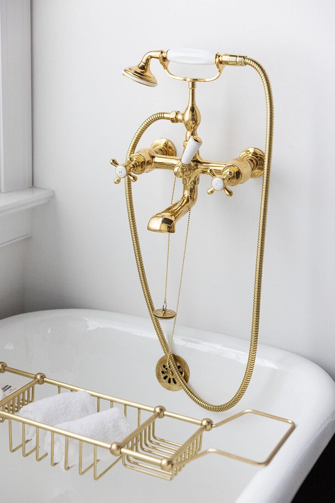 A gold bathroom fixture with a shower head, a handheld shower, and a handheld faucet.